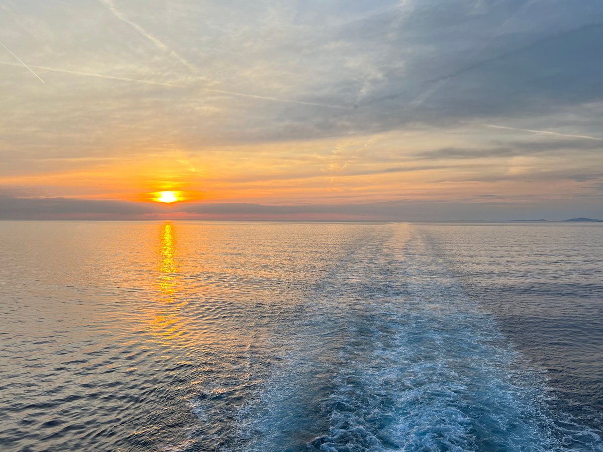 The sun sets across the ocean with a view of the wake left behind from the cruise ship.